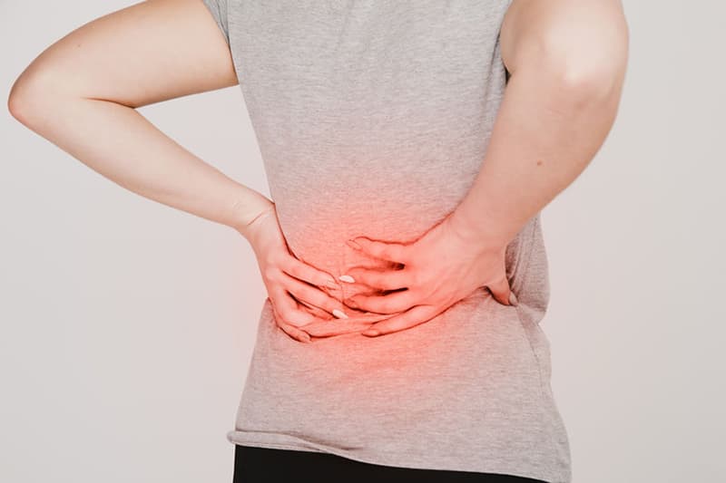 Individual experiencing lower back pain, highlighting the need for the effective osteopathic treatments offered at Triple H Osteocare.